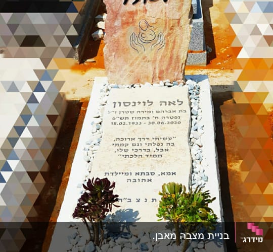 מצבה עם כיתוב בעברית וצמחים קטנים